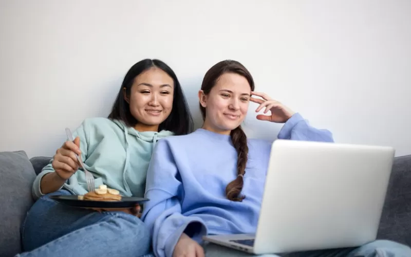 friends watching a video on laptop, group travels, January 2025, UK